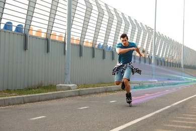 Image of Young man roller skating outdoors. Light trails showing his speed