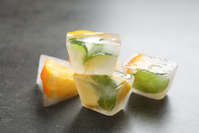 Photo of Ice cubes with orange and mint on grey table