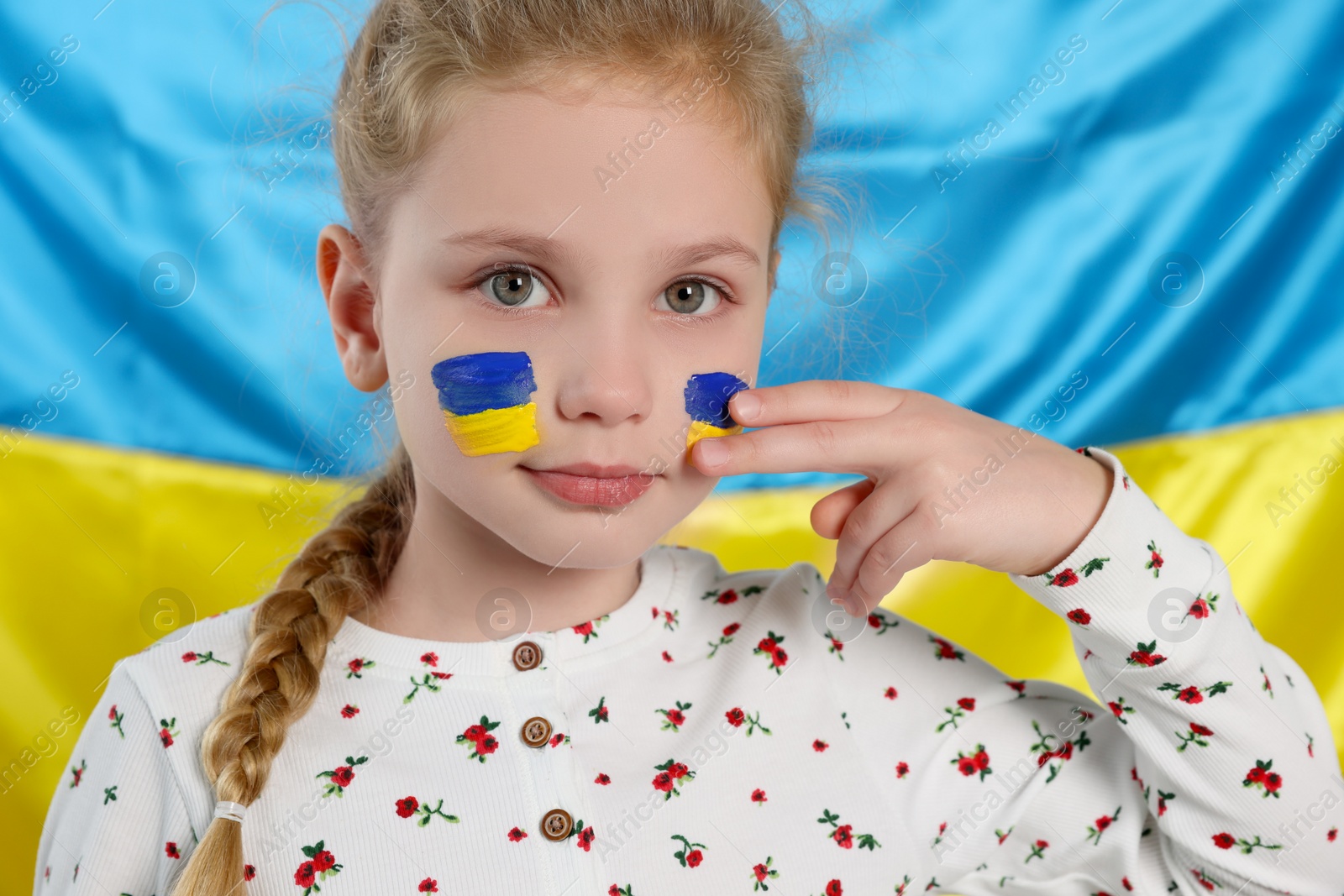 Photo of Little girl with face paint near Ukrainian flag