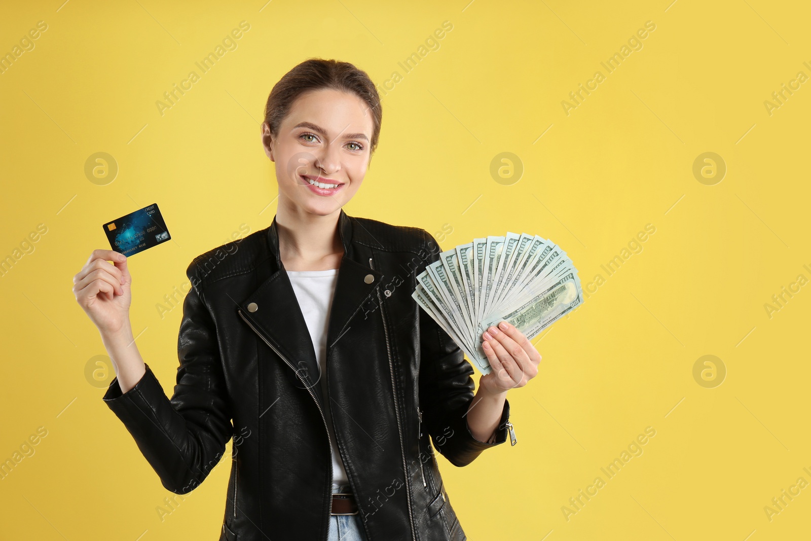 Photo of Young woman with money and credit card on yellow background