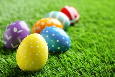 Photo of Colorful painted Easter eggs on green grass, space for text