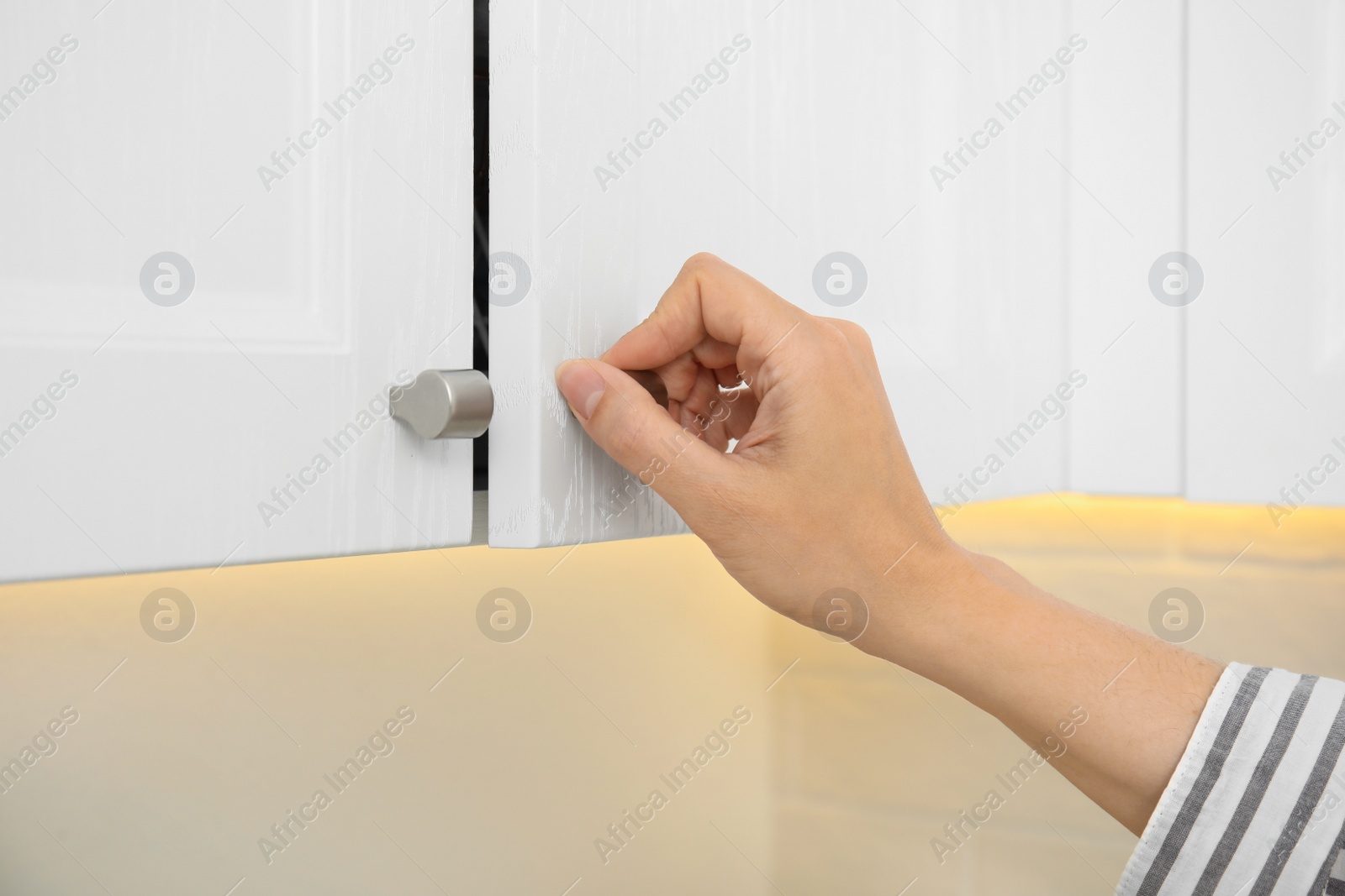 Photo of Woman opening cabinet door at home, closeup