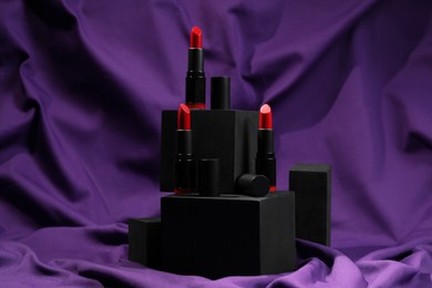 Photo of Stylish presentation of lipsticks on purple fabric