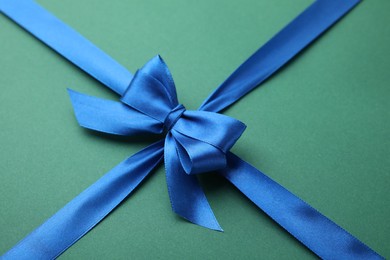 Photo of Blue satin ribbon with bow on green background