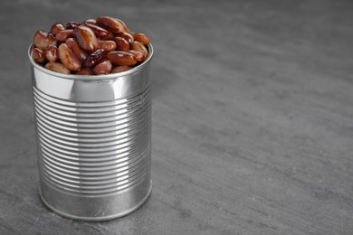 Photo of Tin can with kidney beans on gray table, space for text