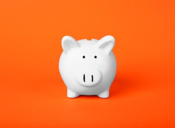 Photo of Ceramic piggy bank on orange background. Financial savings