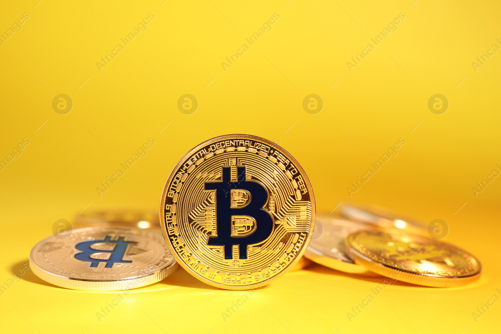 Photo of Shiny bitcoins on yellow background. Digital currency