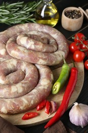 Raw homemade sausages, spices and other products on dark wooden table, closeup