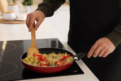 Photo of Man cooking dish on cooktop in kitchen, closeup