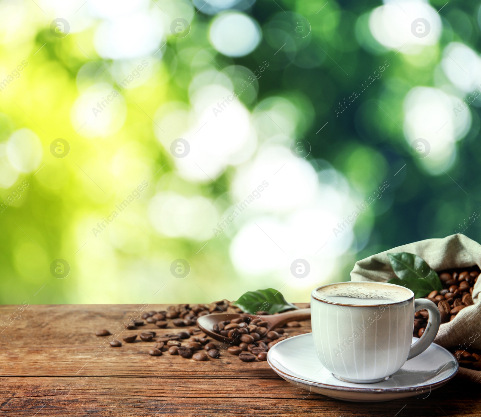 Image of Cup of aromatic hot coffee and beans on wooden table outdoors. Space for text