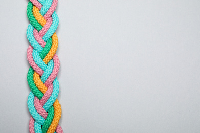 Photo of Top view of braided colorful ropes on light grey background, space for text. Unity concept