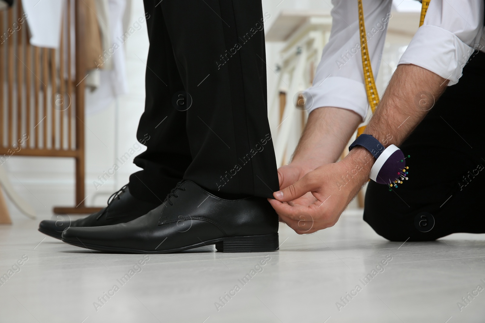 Photo of Professional tailor working with client in atelier, closeup