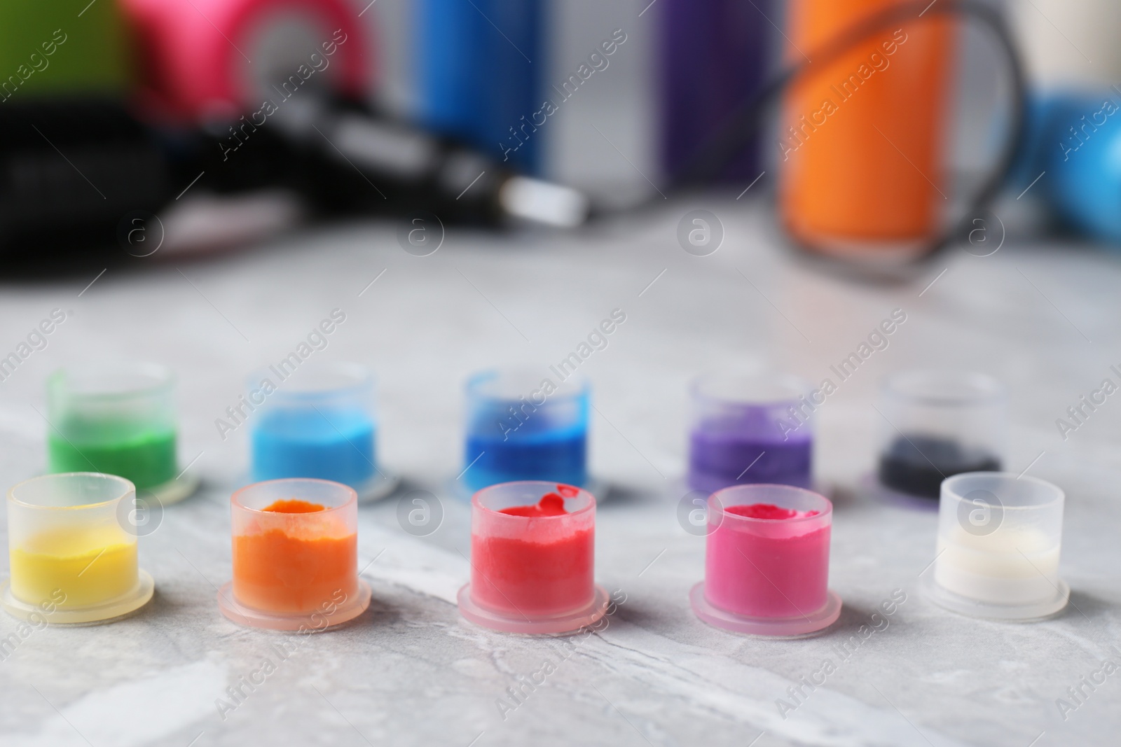 Photo of Tattoo inks and professional tools on light grey table, closeup