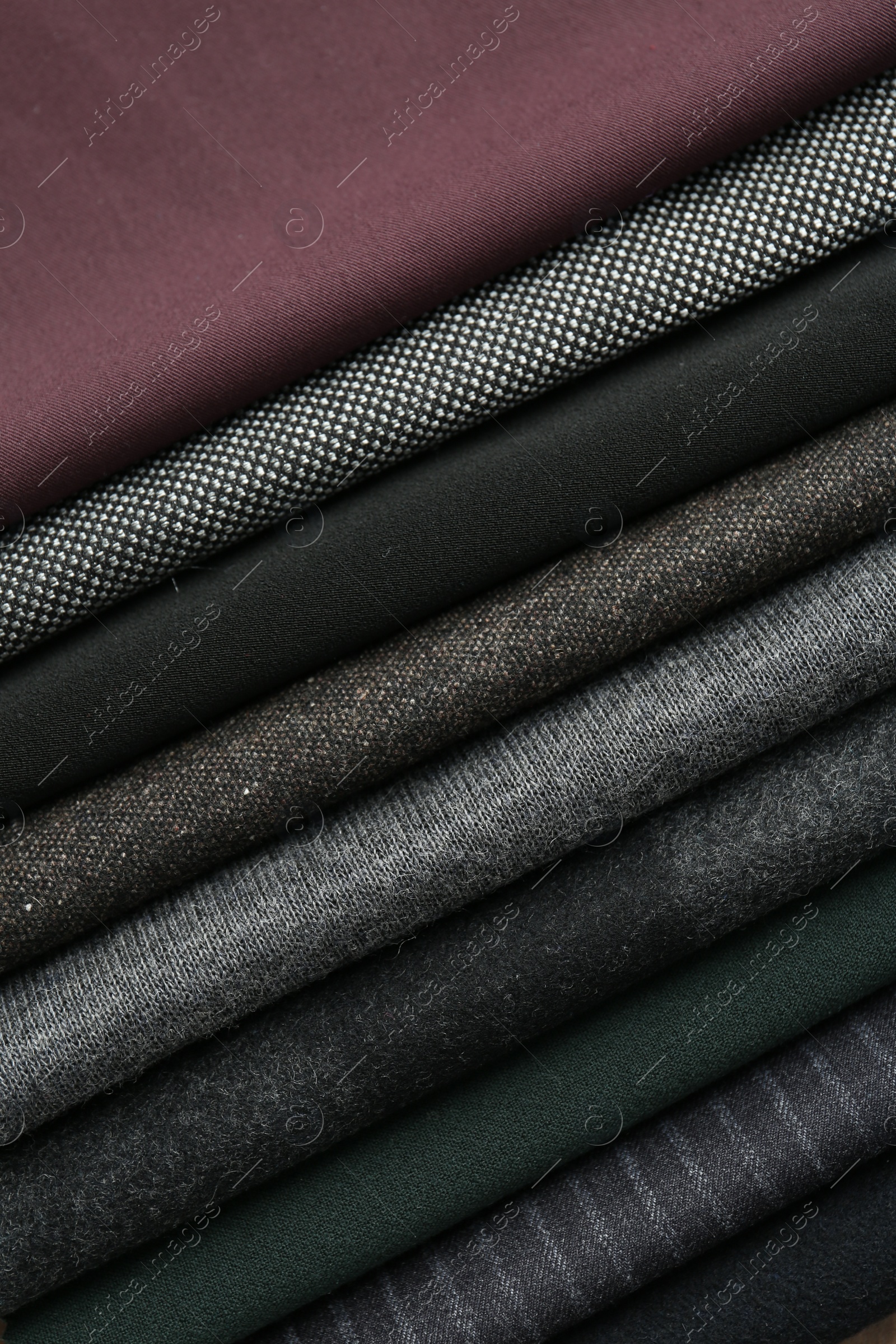 Photo of Stack of different fabric samples as background, closeup. Textile texture