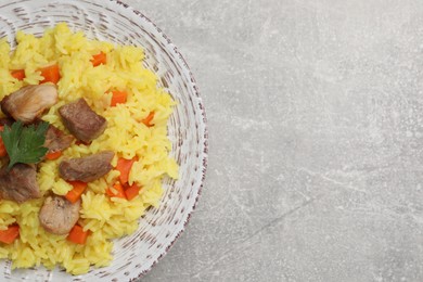 Photo of Delicious pilaf with meat on light grey table, top view. Space for text