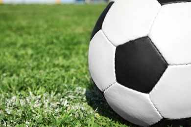 Photo of Soccer ball on fresh green football field grass, closeup. Space for text