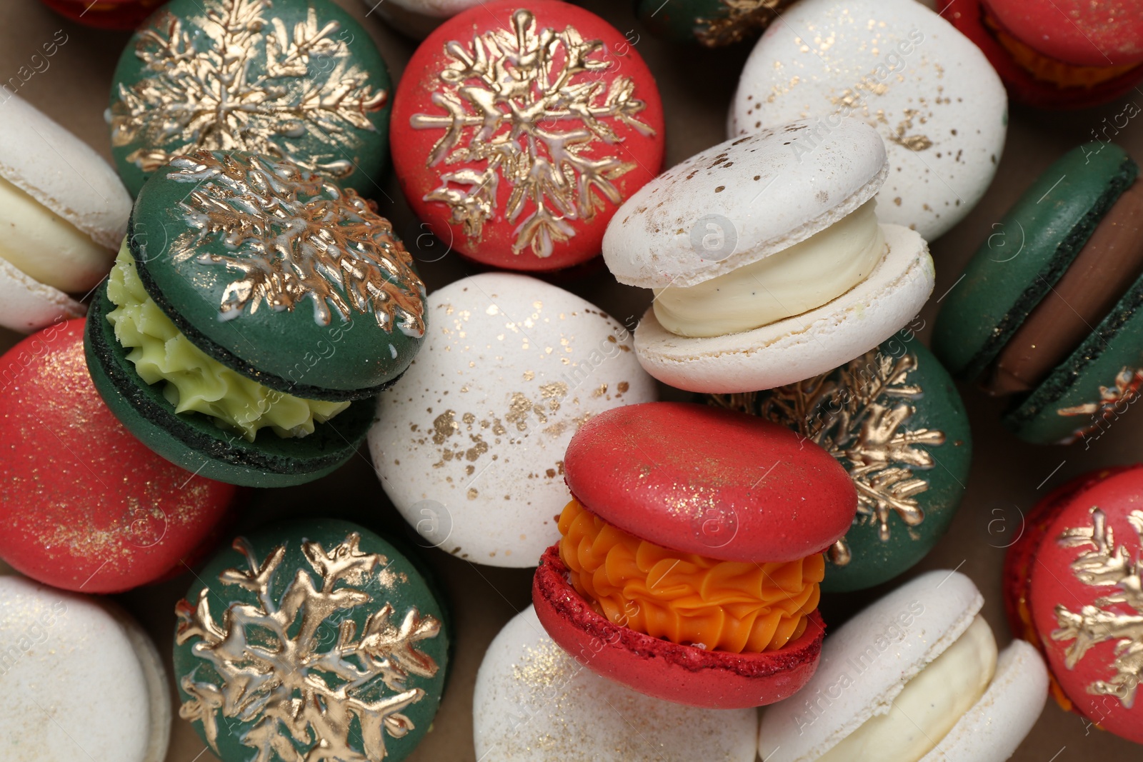 Photo of Beautifully decorated Christmas macarons on brown background, top view