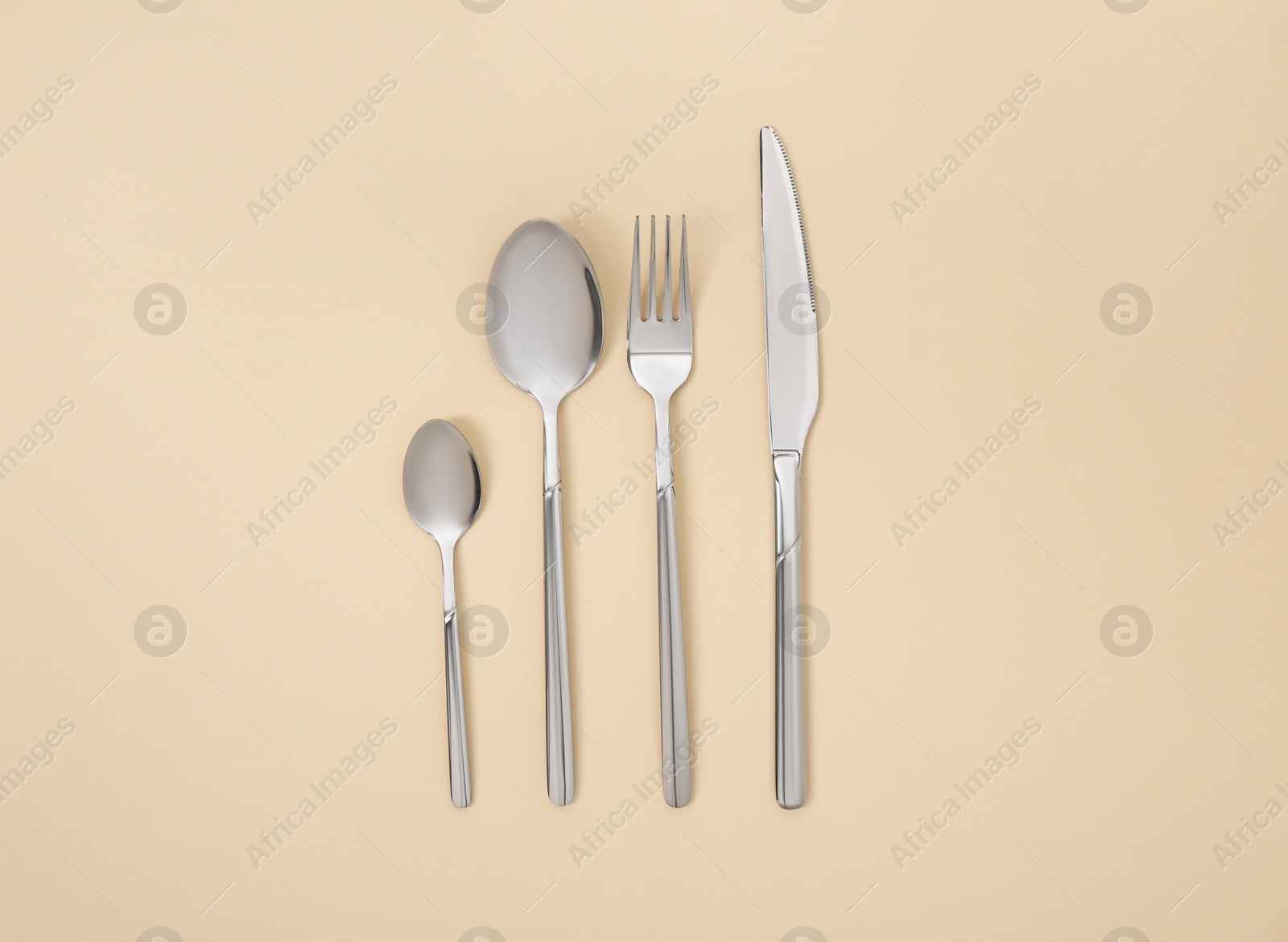 Photo of Stylish silver cutlery set on beige background, flat lay