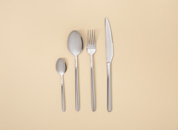 Stylish silver cutlery set on beige background, flat lay