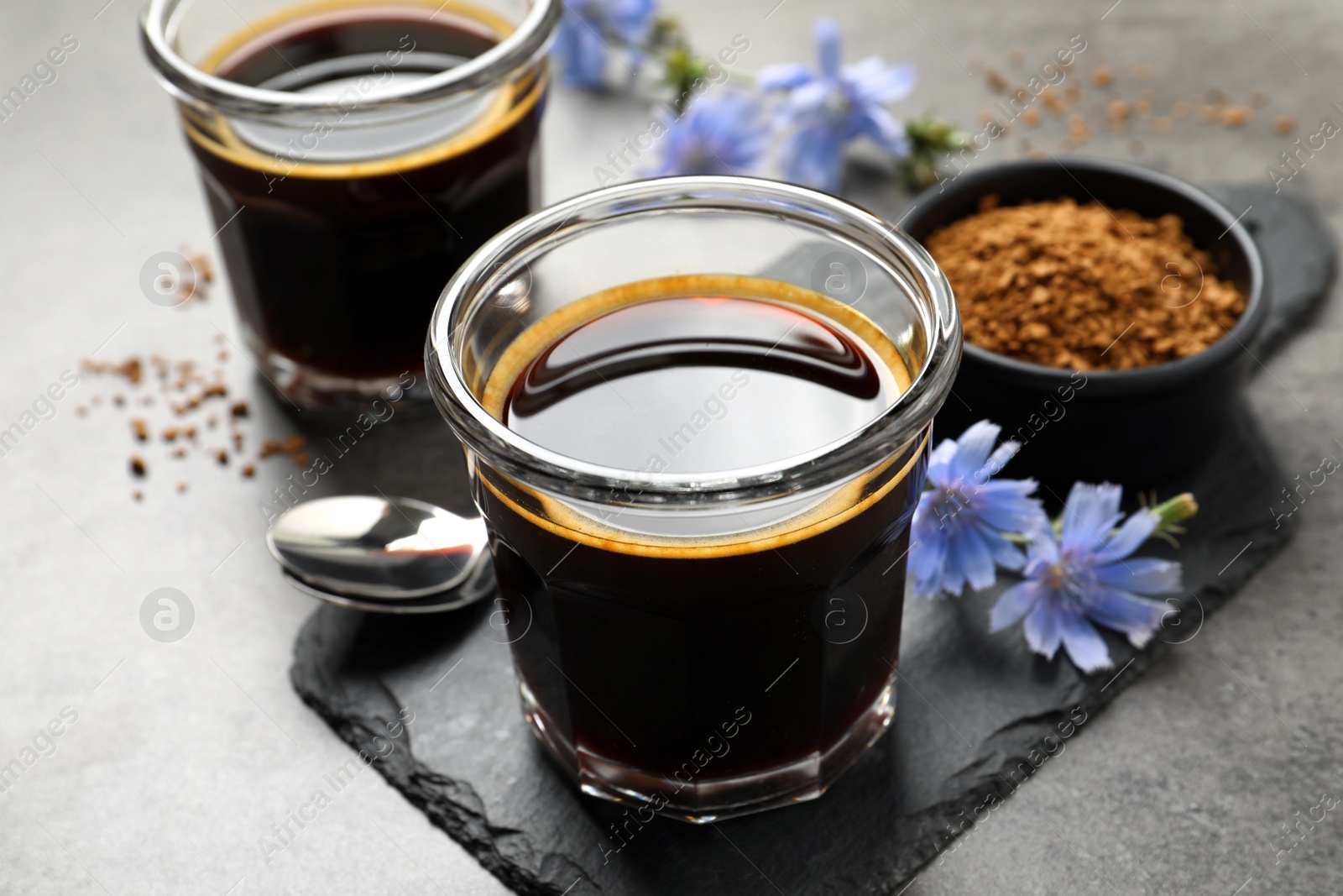 Photo of Delicious chicory drink and flowers on grey table, closeup