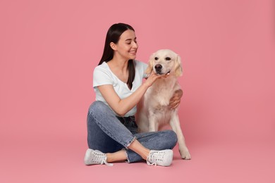 Happy woman with cute Labrador Retriever dog on pink background. Adorable pet