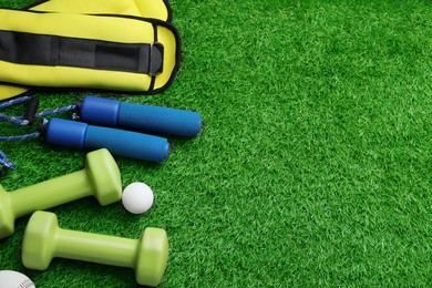 Photo of Setdifferent colorful sports equipment on green grass, above view. Space for text