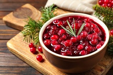 Photo of Fresh cranberry sauce with rosemary on wooden board