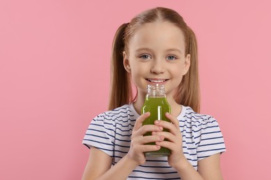 Photo of Little girl drinking fresh juice on pink background. Space for text
