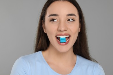 Woman with bubble gum on grey background