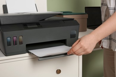 Woman using modern printer at workplace, closeup