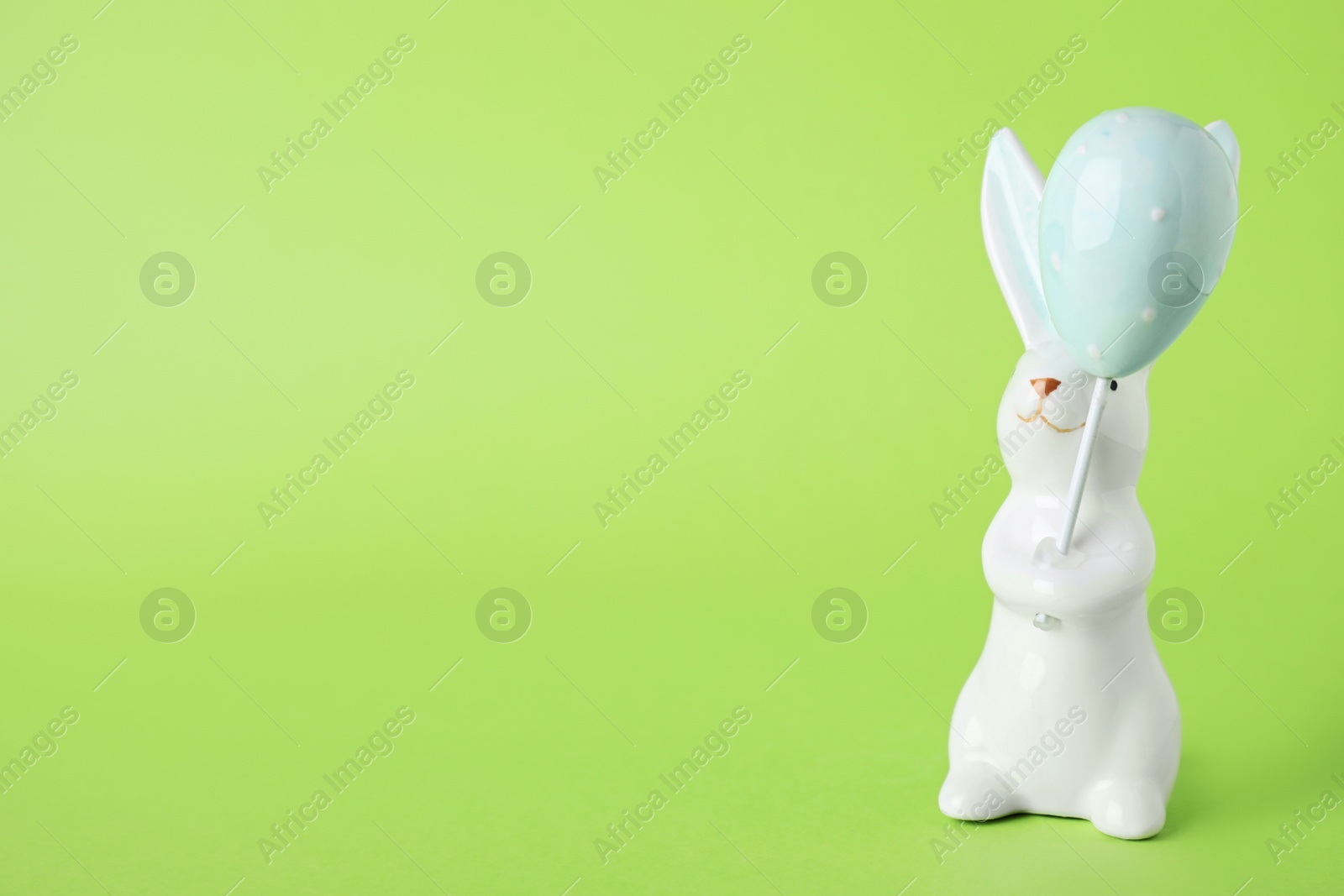 Photo of Easter bunny figure on green background. Space for text