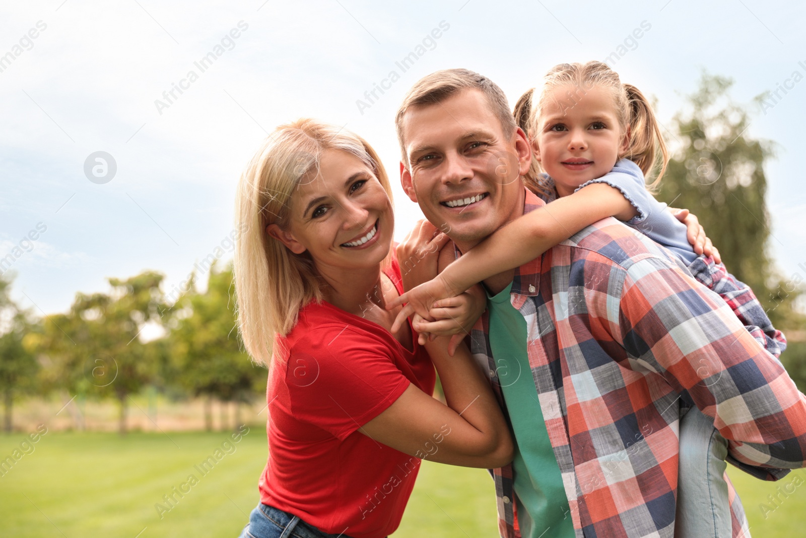 Photo of Cute little girl having fun with her parents in park on summer day