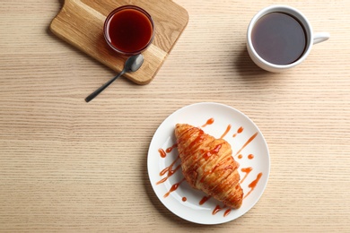 Plate of fresh croissant served on wooden table, flat lay. French pastry