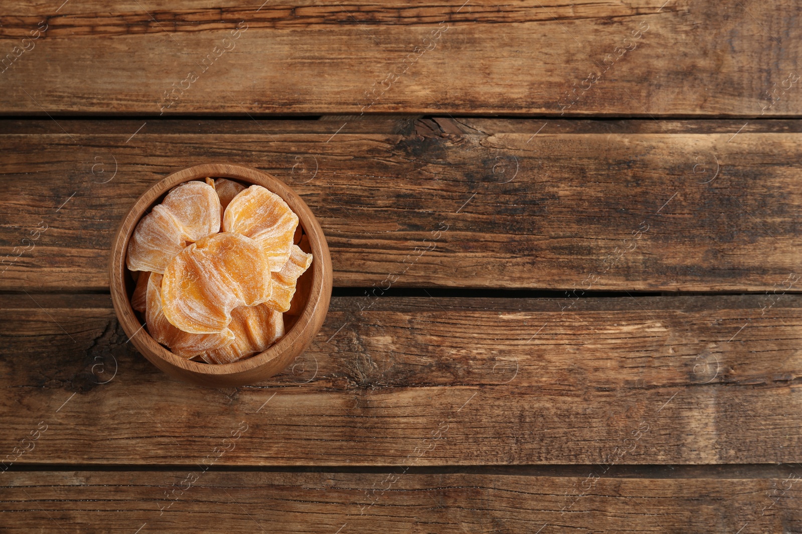 Photo of Delicious dried jackfruit slices in bowl on wooden table, top view. Space for text