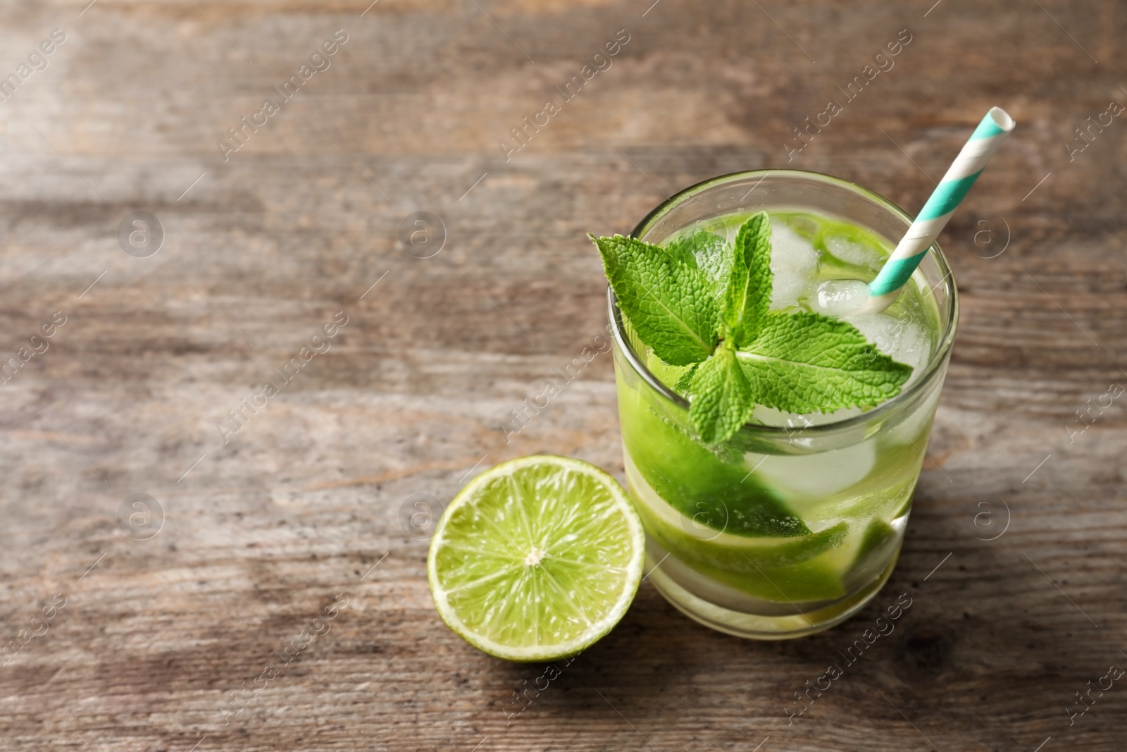 Photo of Refreshing beverage with mint and lime in glass on table