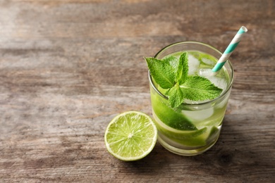 Photo of Refreshing beverage with mint and lime in glass on table