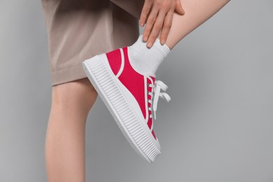 Woman posing in red classic old school sneakers on light gray background, closeup