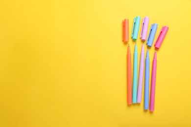 Photo of Many colorful markers on yellow background, flat lay. Space for text