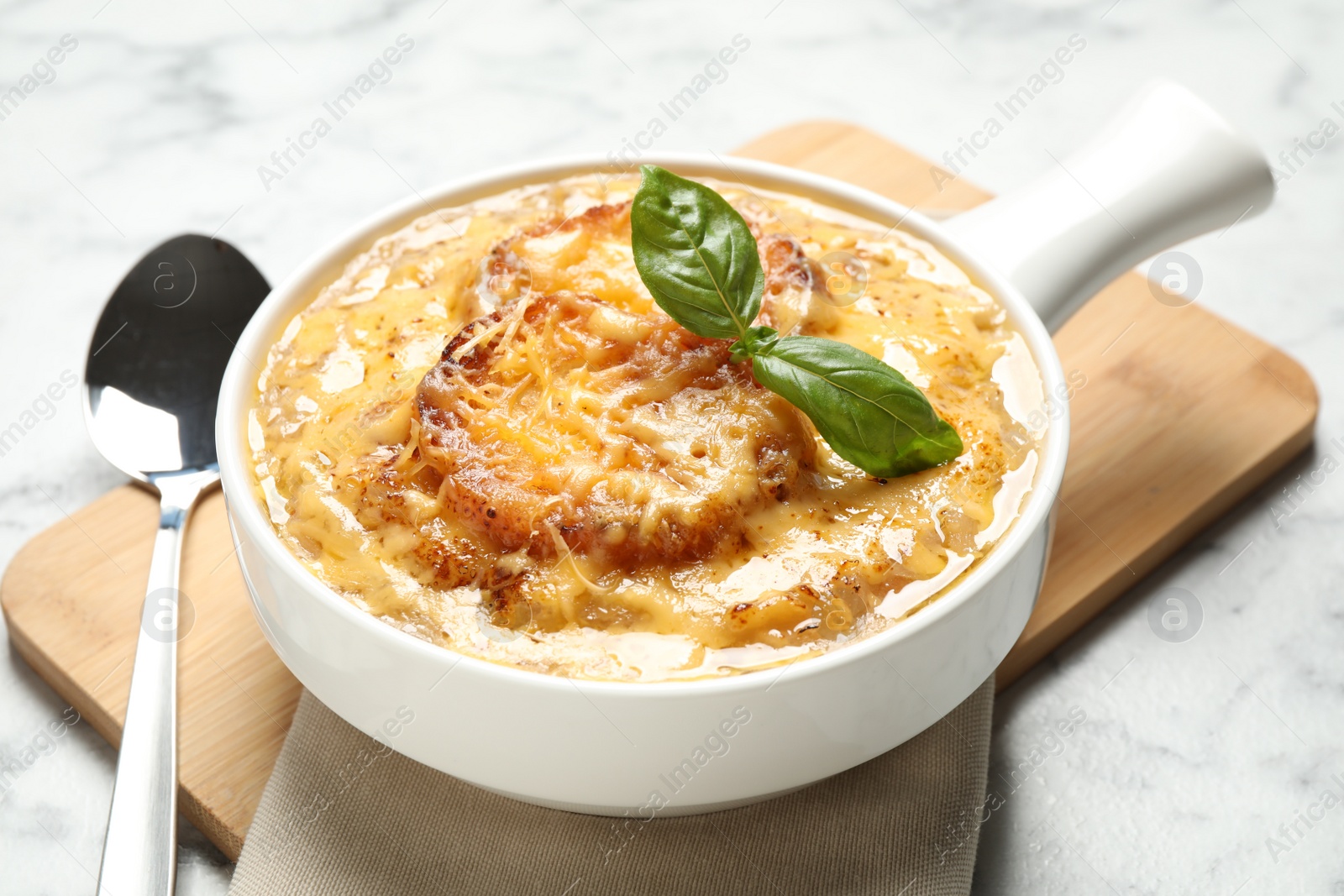 Photo of Tasty homemade french onion soup served on light table, closeup