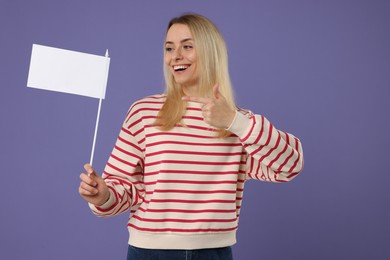 Happy woman pointing at blank white flag on violet background. Mockup for design