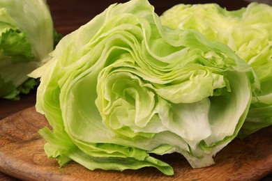 Photo of Board with halves of fresh green iceberg lettuce head on wooden table, closeup