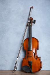 Photo of Beautiful violin and bow on wooden table near light blue wall