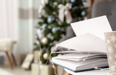 Photo of Book and Christmas lights on table in stylish living room interior