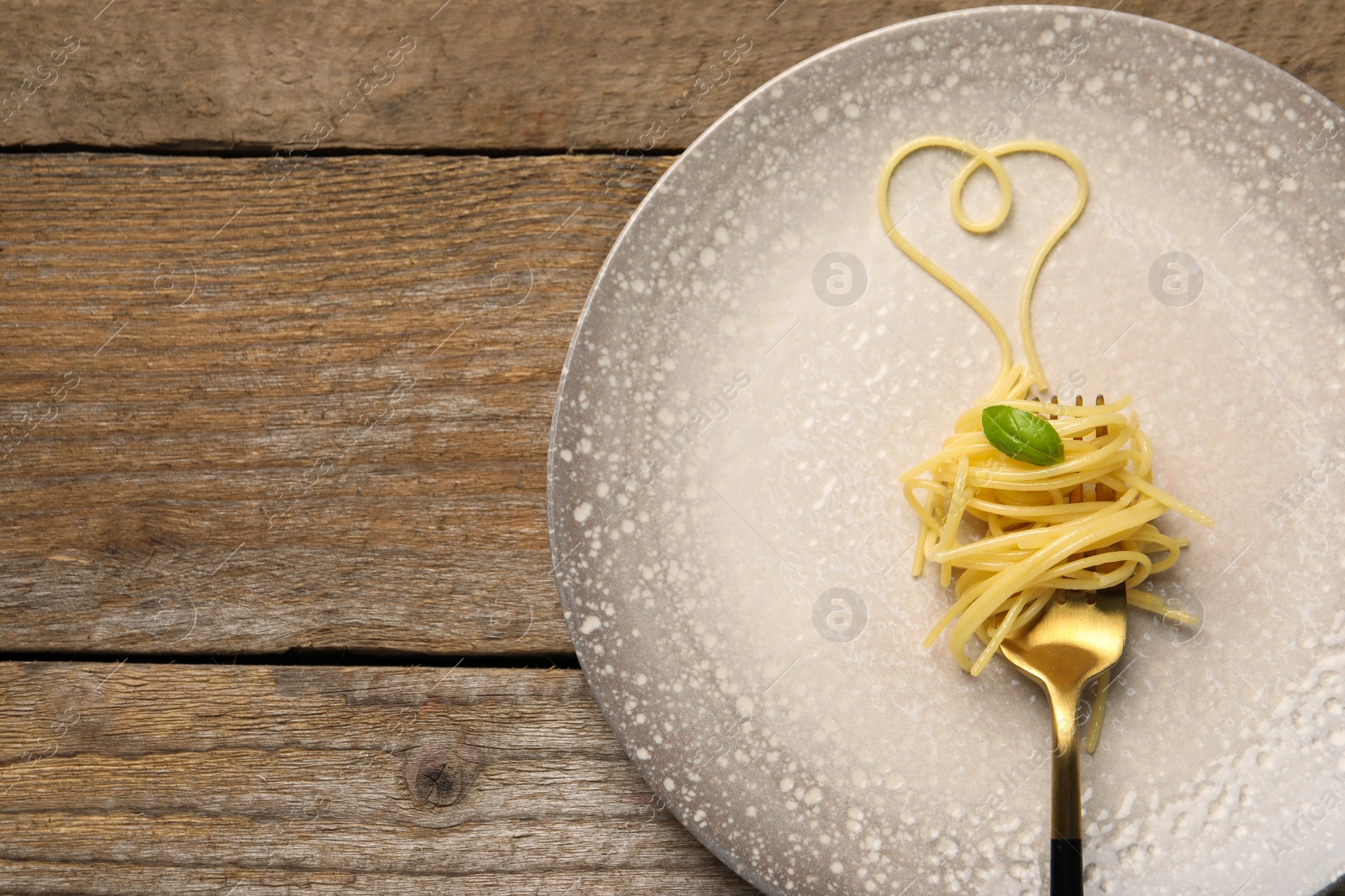 Photo of Heart made with spaghetti and fork on wooden table, top view. Space for text