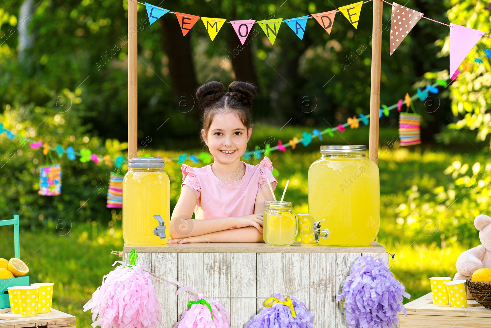 Photo of Cute little girl at lemonade stand in park. Summer refreshing natural drink