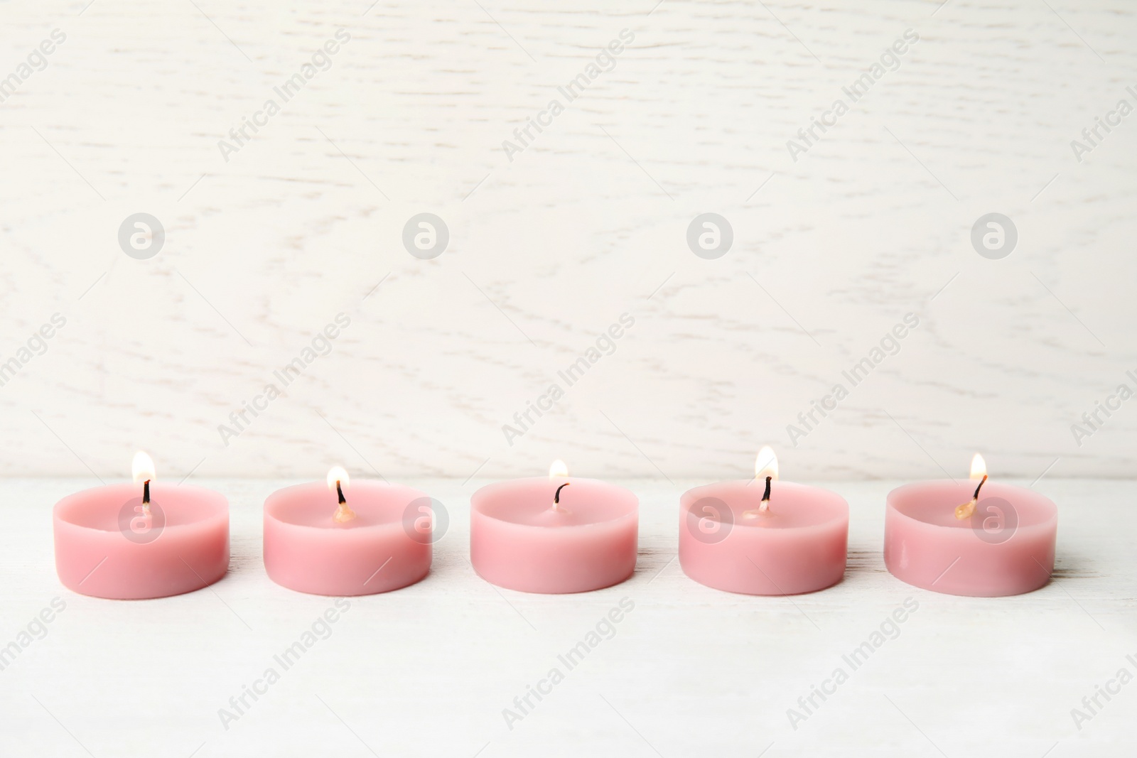 Photo of Pink wax candles on white table, space for text