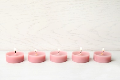 Pink wax candles on white table, space for text