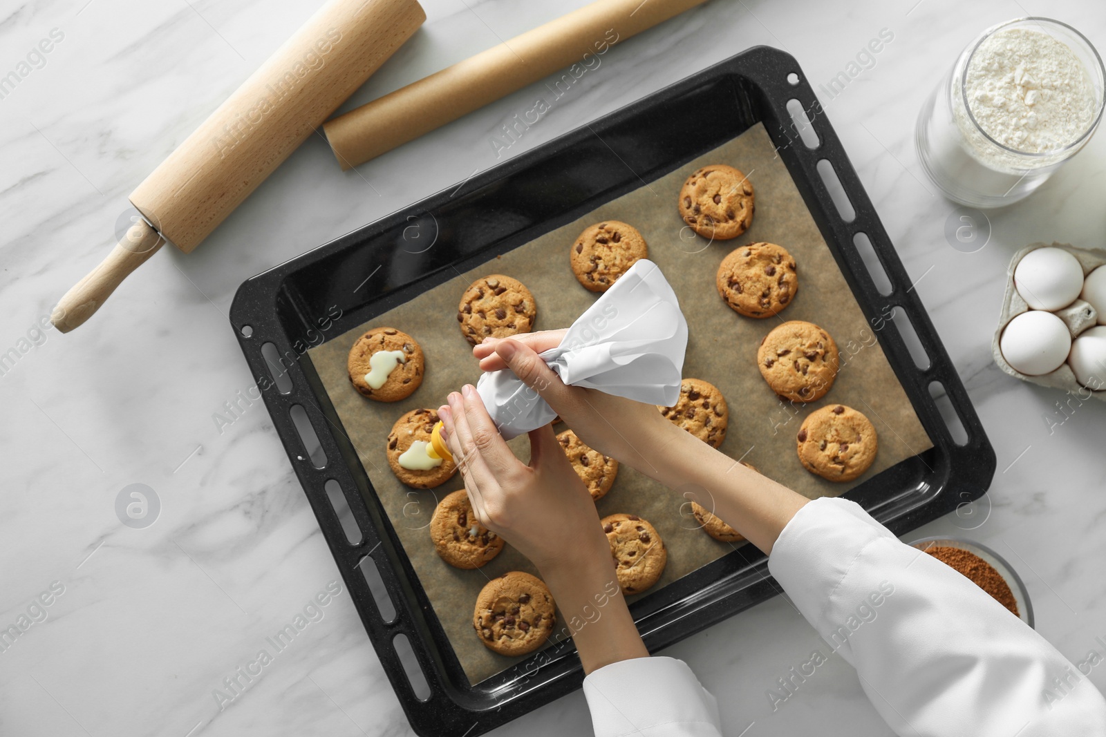 Photo of Woman preparing biscuits at white marble table, top view. Cooking delicious food