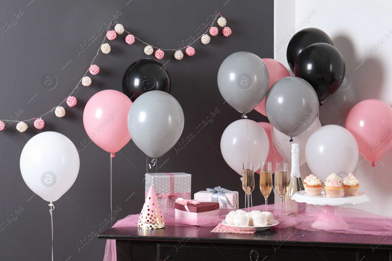 Photo of Party treats and items on table in room decorated with balloons