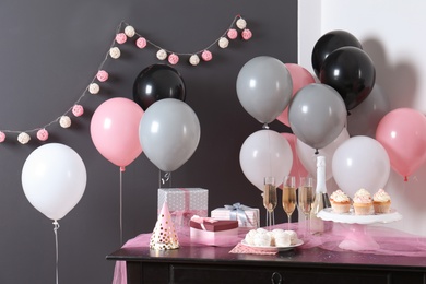 Party treats and items on table in room decorated with balloons